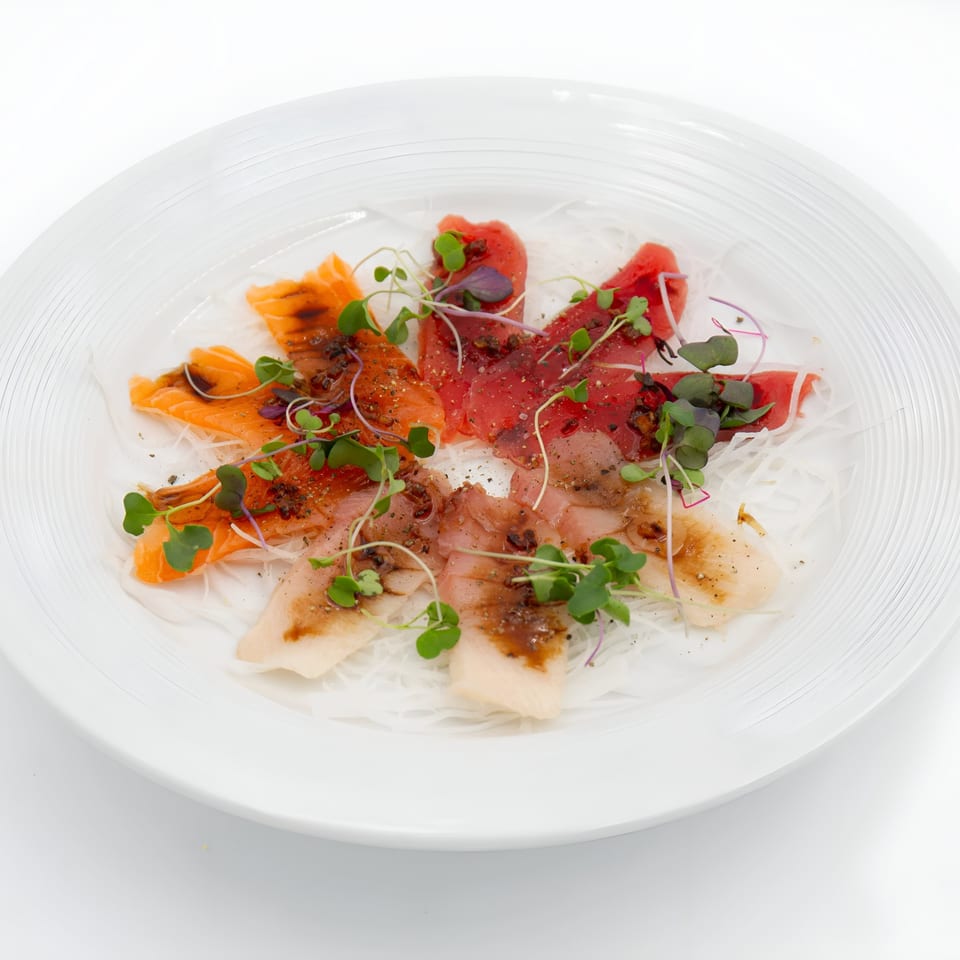 Jade Lowell's colorful sashimi platter with salmon, tuna, and white fish, garnished with microgreens.