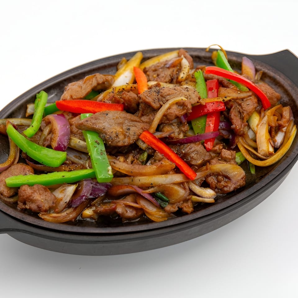 Jade Lowell's sizzling beef with bell peppers and onions in a black skillet.