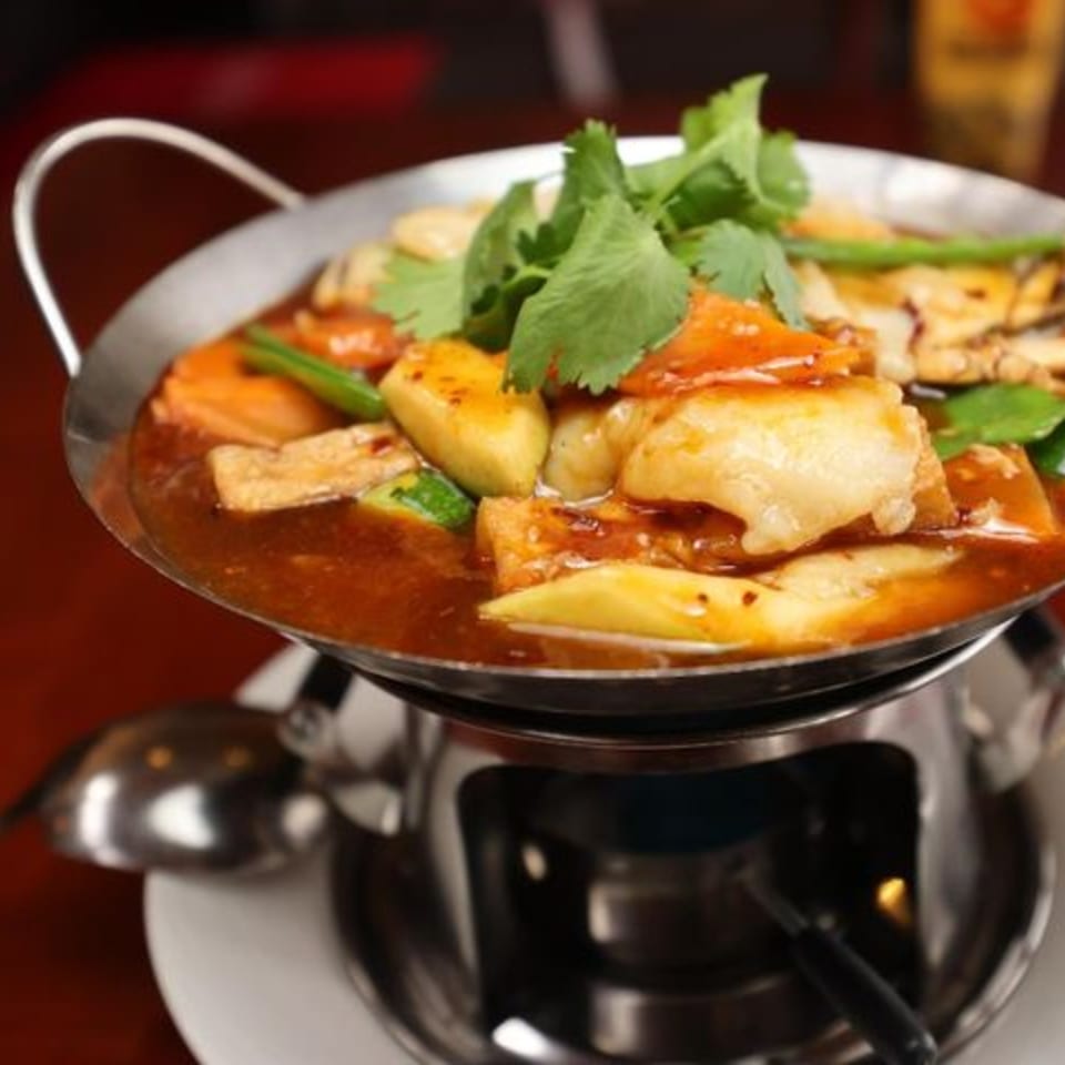Jade Lowell's Asian-fusion hot pot with fish, vegetables, and cilantro, simmering over a flame.